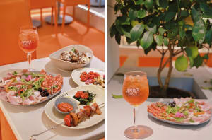 A warm and inviting dining area in an orange-themed restaurant with plates of food and a wine glass on a table, accompanied by a potted plant