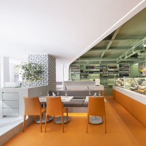 Warm and inviting dining space with an orange background, a large wooden dining table, and wine glasses on the table