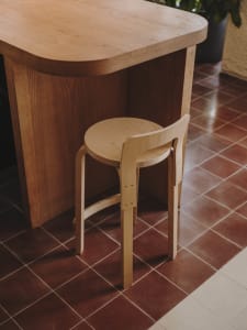 A minimalist dining space with a wooden table and chair, set against a tiled floor