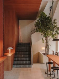 A hotel staircase with wooden steps and a black railing, accompanied by two chairs for guests to rest or wait