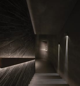 A darkened room with a stone staircase featuring two sets of steps, one on each side of the room