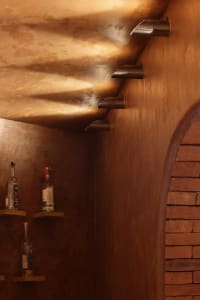 A cozy room with a brick wall, a shelf with two bottles, and a rustic atmosphere