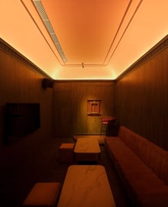 A well-lit living space with a marble dining table, two couches, and a warm atmosphere