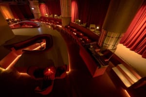 A modern restaurant with red walls, curtains, and chairs, featuring dining tables and a comfortable atmosphere