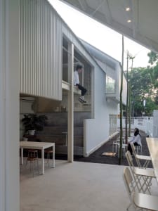 A modern living-dining space with white walls, wooden furniture, and a relaxed atmosphere, featuring a person sitting on a chair