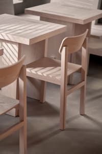 Warm dining space with two wooden tables and four chairs, surrounded by a cozy atmosphere