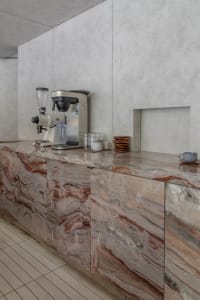 A clean and organized kitchen with a marble countertop featuring cups, bowls, and a blender, adding an elegant touch to the space