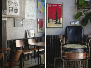 A restaurant interior with two chairs, three dining tables, posters, plants, and a mix of old and modern decor