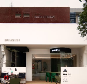 Inviting storefront with a white building, green chairs, and dining tables, encouraging customers to explore the interior design offerings