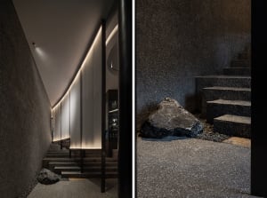 Contemporary building with black stone wall and metal railing, featuring a staircase and sleek design