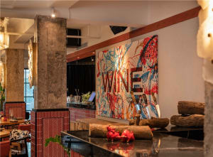 A wine bar scene with a large painting on the wall featuring wine bottles, cups, and bowls in a vibrant and inviting atmosphere