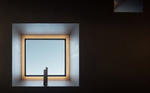 Empty room with a large window and wooden walls, featuring a calm and serene atmosphere with natural light and simplicity