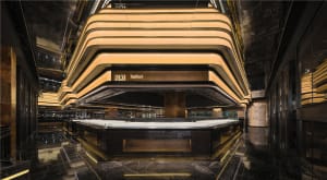 A spacious hotel lobby with high ceilings, gold accents, and several people enjoying the inviting atmosphere