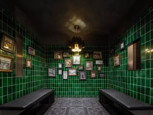 A well-lit bathroom with green tiles, a bench, and wall decorations, creating a bright and inviting atmosphere