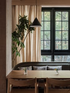 Cozy living space with a dining table, chairs, vases, and a potted plant, surrounded by windows for natural light
