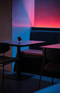 Cozy cafe interior with wooden tables, benches, and a small black box on one table, creating a warm and inviting atmosphere
