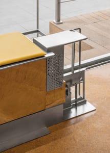 A wooden bench with a yellow seat sits on a tile floor, accompanied by a chair, creating a comfortable and inviting atmosphere