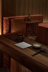 A well-lit room with a wooden desk, a bowl, a cup, a book, and a vase, suggesting a comfortable and inviting living space