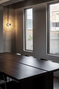 Empty dining area with a wooden table and chairs, surrounded by large windows allowing natural light to enter