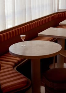 A dining area with two tables and multiple chairs, a wine glass, and an inviting atmosphere