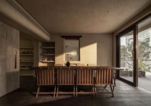 A warm and inviting living area with a wooden dining table and chairs, surrounded by natural light from the windows