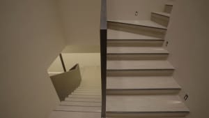 A photo of a staircase with a black railing in an indoor setting