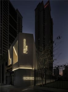 A modern building with a concrete structure and a prominent sign, set against a dark night sky