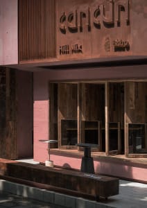 Warm and inviting restaurant interior with a wooden bar, pink accent wall, and rustic wooden furniture