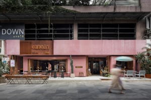 Outdoor cafe with pink building, chairs, tables, umbrellas, and people