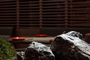 Modern interior design concept featuring a rock wall with red plates on a table in front, creating a stylish display