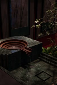 A modern bathroom with a large stone sink basin featuring a marble finish and flowing water, set against a neutral background