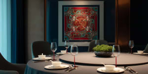 Elegant dining area with a round table set for dinner, featuring wine glasses, cups, and utensils, surrounded by four chairs