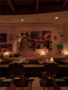 A cozy dining area with a long wooden table surrounded by chairs, wine glasses, and bottles, creating a warm and inviting atmosphere