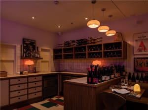 A kitchen with a dining table, wine bottles, and cups, creating a cozy and inviting atmosphere for food and drink preparation