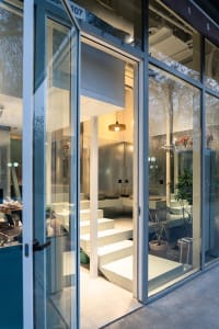 Open living area with white walls and floors, featuring potted plants and decorative vases, with bright and inviting atmosphere and ample natural light