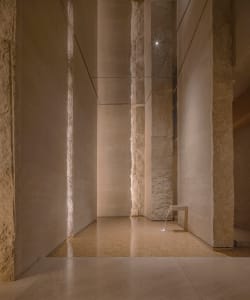Empty lobby with a glass wall, two benches, and natural light creating interesting shadows on the walls and floors