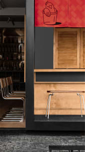 A warm and inviting bar area with wooden elements, including a wooden countertop and chairs, and bottles placed on the countertop