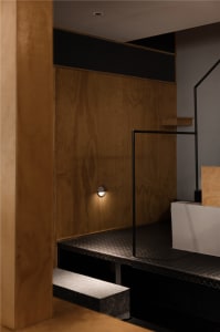 Dimly lit room with wooden walls and floors, featuring two sets of stairs and a cozy atmosphere