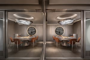 A well-lit restaurant dining area with multiple round tables and chairs, gray and white walls, and a comfortable atmosphere