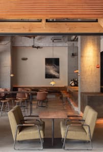 Modern restaurant interior with dining tables, chairs, and potted plants, creating a comfortable atmosphere