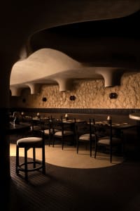 Cozy restaurant interior with stone walls, tables, chairs, and a warm atmosphere