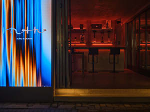 A modern bar with a glass front and three chairs placed around a counter, creating an inviting atmosphere for socializing over drinks or meals