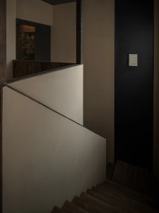 A photo of a staircase in a modern building with wooden stairs and a black wall, creating a sense of depth and dimension