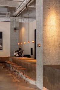 Industrial bar area with a modern concrete bar, stools, and chairs in a minimalist and functional space