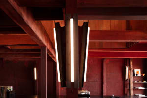 Dining space with red walls, wooden beams, and overhead lighting, featuring a table and warm atmosphere