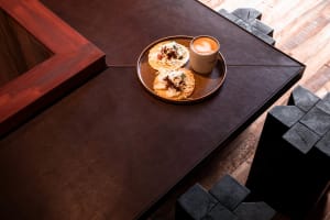 A casual dining setting with a wooden table, two plates of food, and cups of coffee