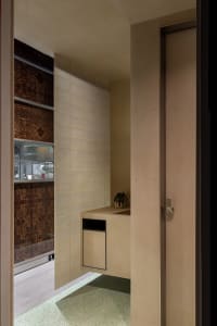 Small bathroom with brown tile walls, a sink, toilet, and shower area, featuring a potted plant on the countertop