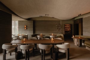 Elegant restaurant dining area with a large wooden table and chairs, wine glasses, and a sophisticated atmosphere