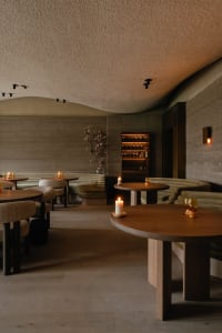 Warm and inviting restaurant interior with wooden tables and chairs, dimly lit for an intimate ambiance