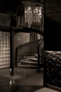 A dimly lit staircase in a restaurant or bar with signs indicating smoking and non-smoking areas, leading to a lower level